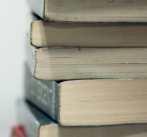 A collection of books stacked on a table, showcasing different colors and sizes.