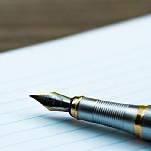 A fountain pen resting on an open notepad, ready for writing.