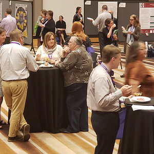 A group of people seated at tables in a conference room during a teaching conference, engaged in discussion and learning.