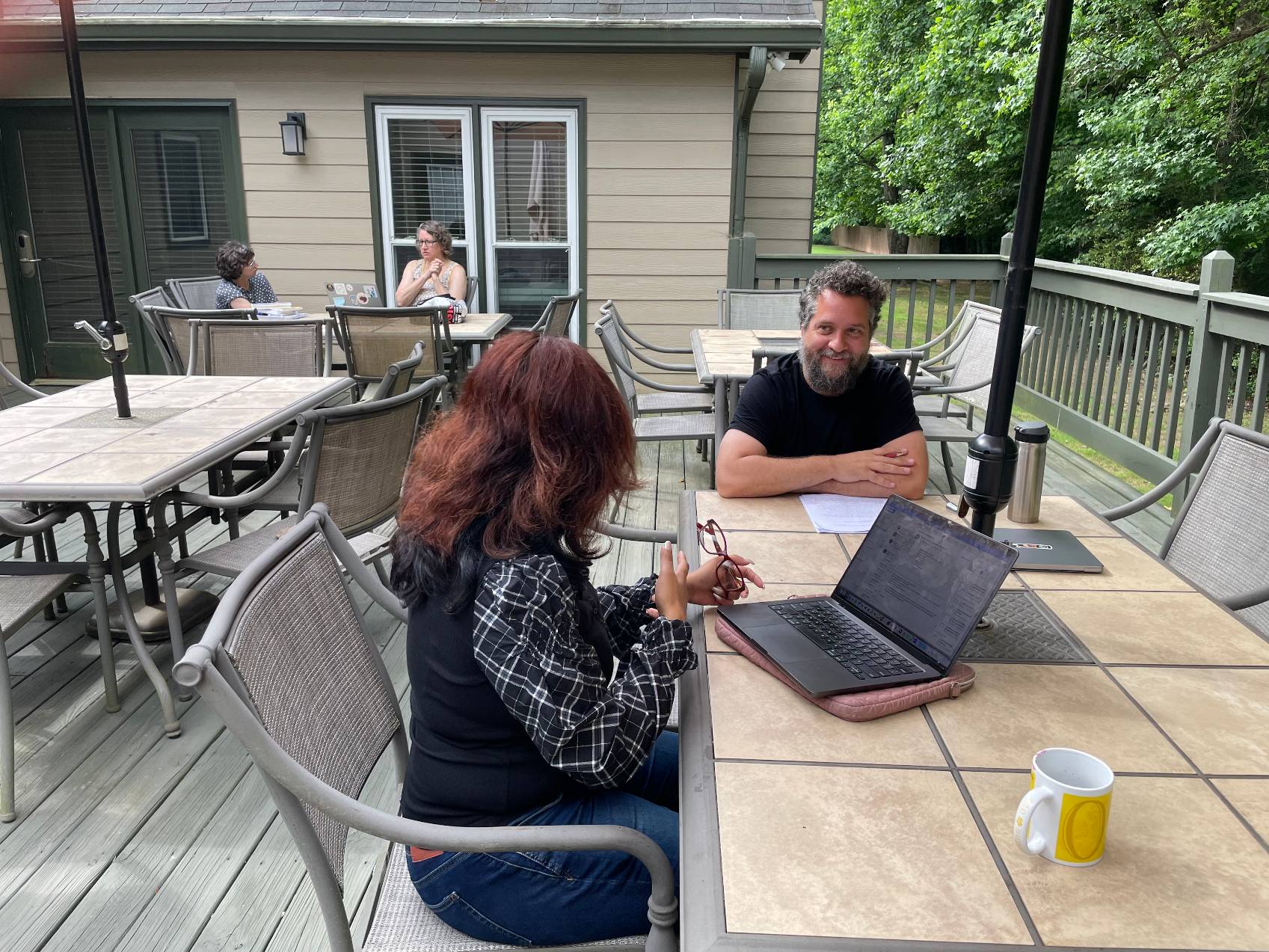 two faculty members having a dicussion at a table outside on the cetl house deck 