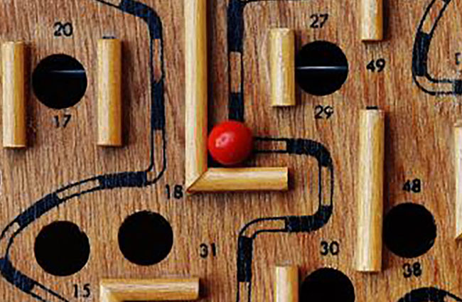 A wooden maze featuring several red balls positioned throughout its pathways.