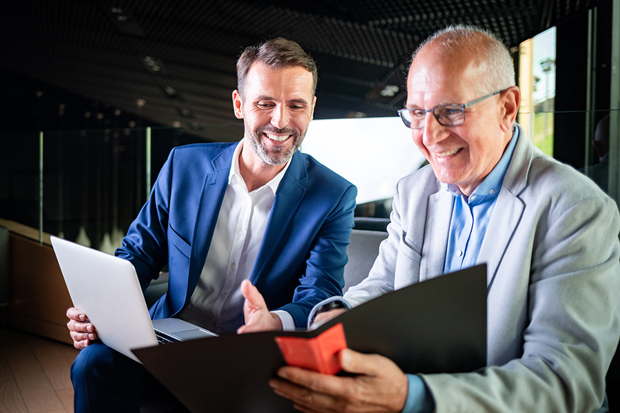 a photo of two men looking over papers and folders