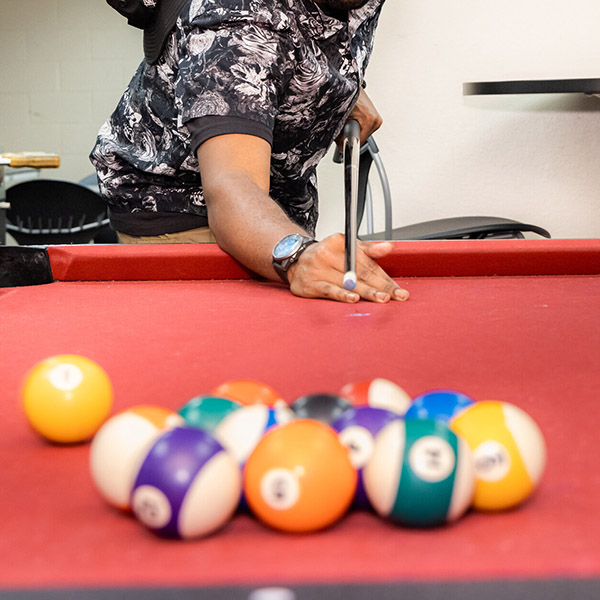 a student lines up a shot at a pool table