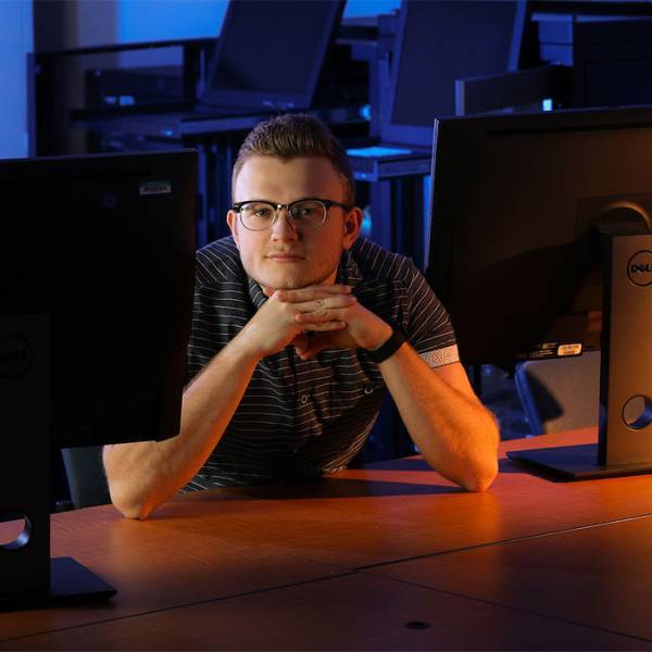 KSU information systems student sitting a desk with several computer monitors