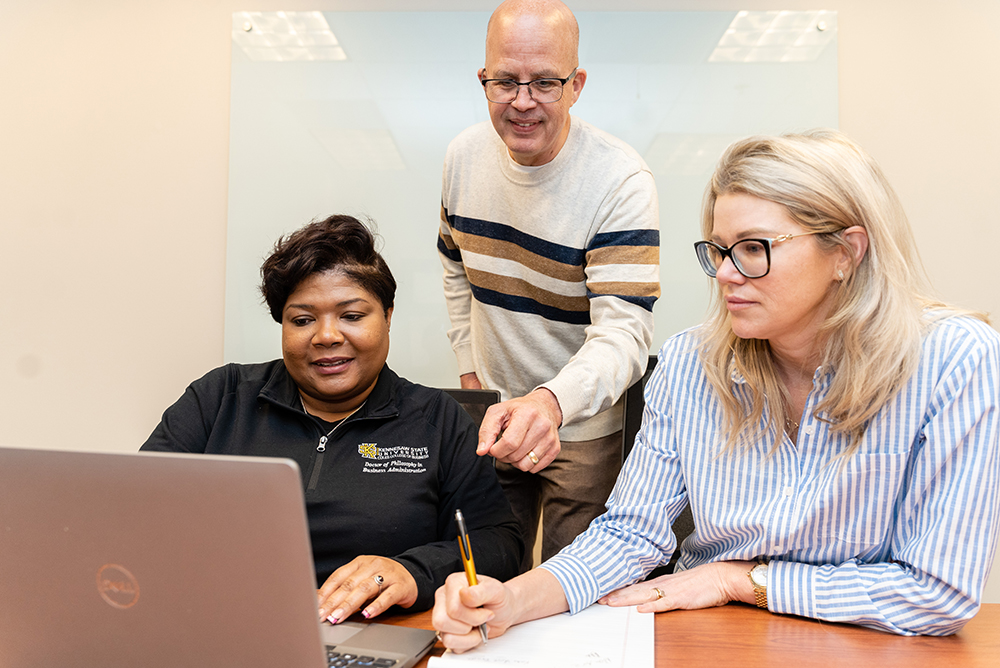 Ph.D. in Business Administration students with a faculty member discussing an assignment