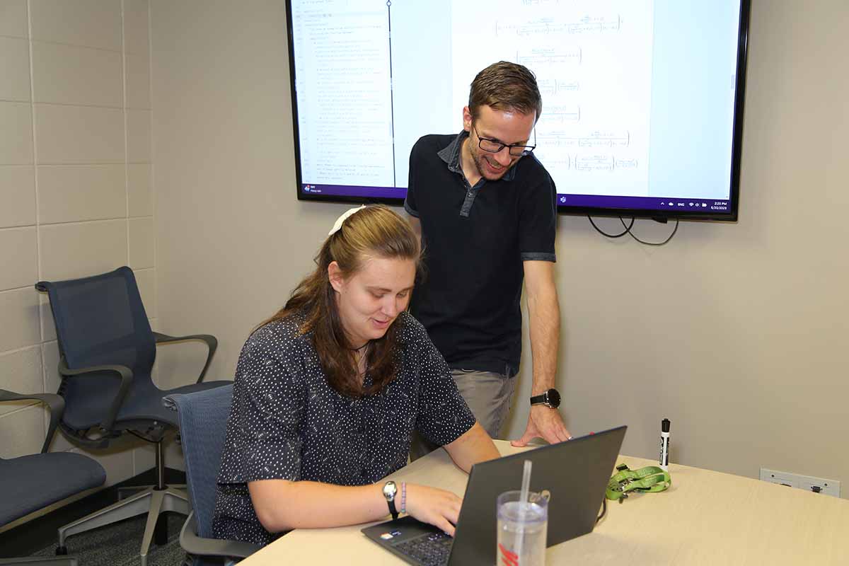 Faculty and student working on research on a computer. / Faculty and student working on research on a computer.