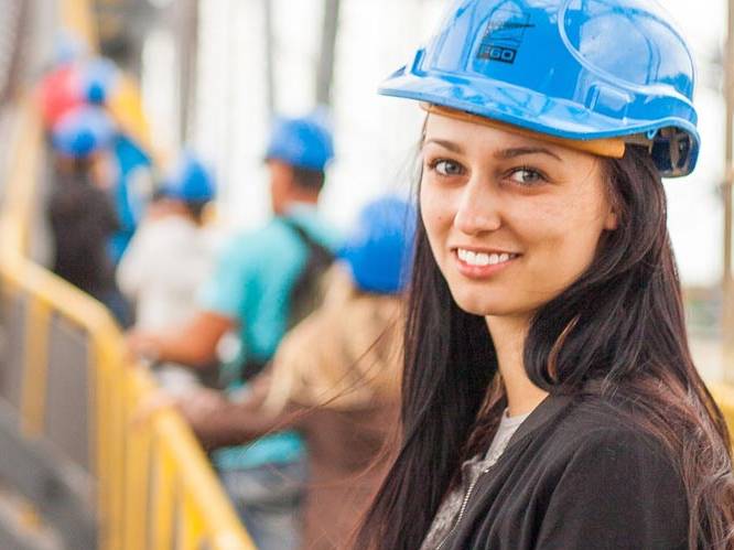 Young woman has a blue hard hat on at a construction site