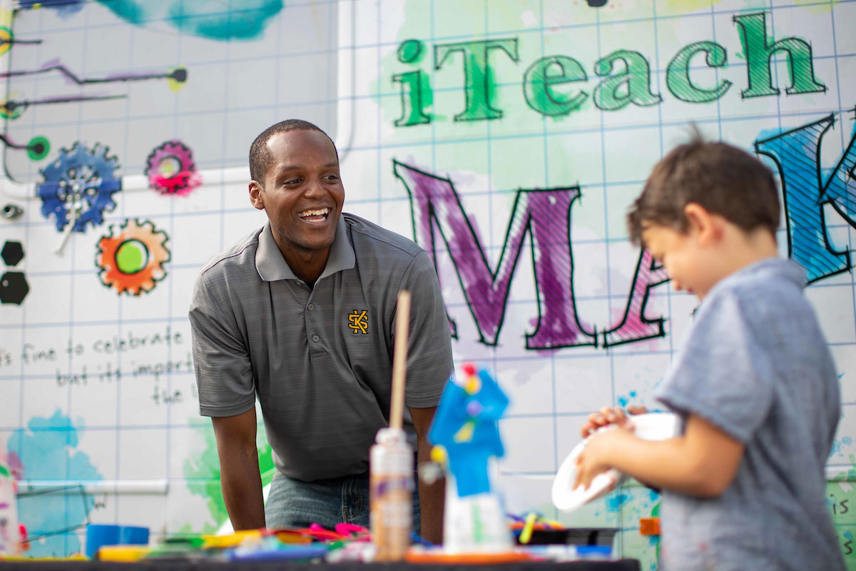 Man is smiling at young child working on project