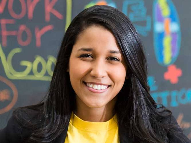 Business student smiling for picture with a colorful chalk board behind her