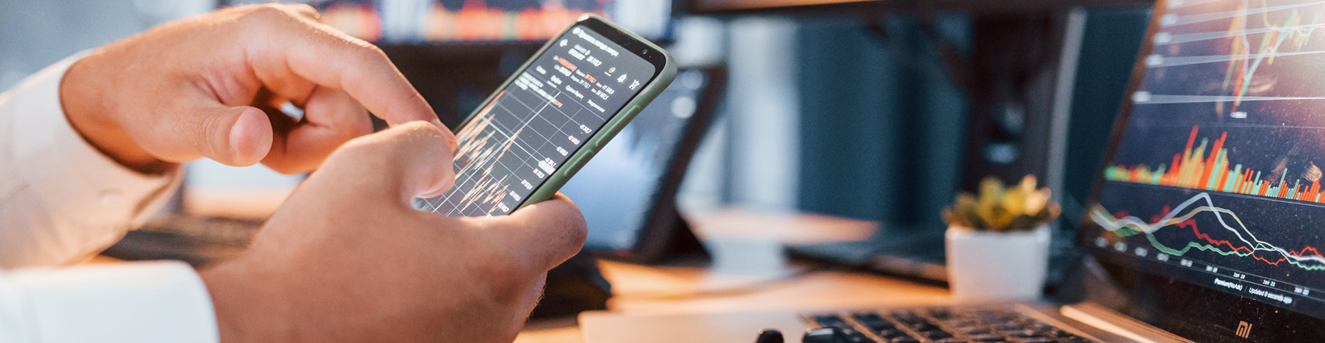 close up of a mans hands as his pointing to data charts on his cell phone