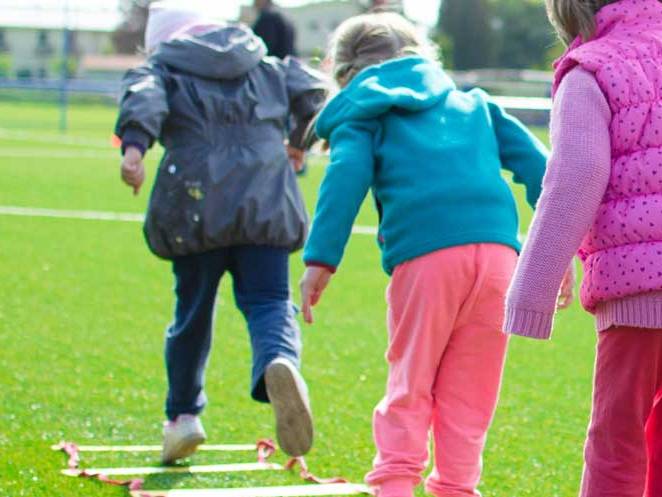 three younger children playing with a flat ladder