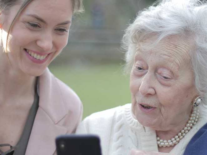 Woman and a elder woman looking at a phone communicating