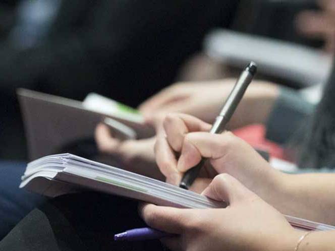 Student is seated and writing in a journal with a pen