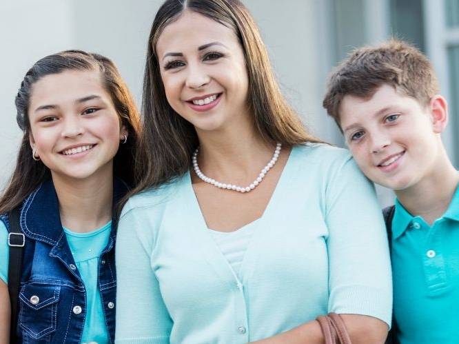 Woman and younger children standing together smiling for a picture