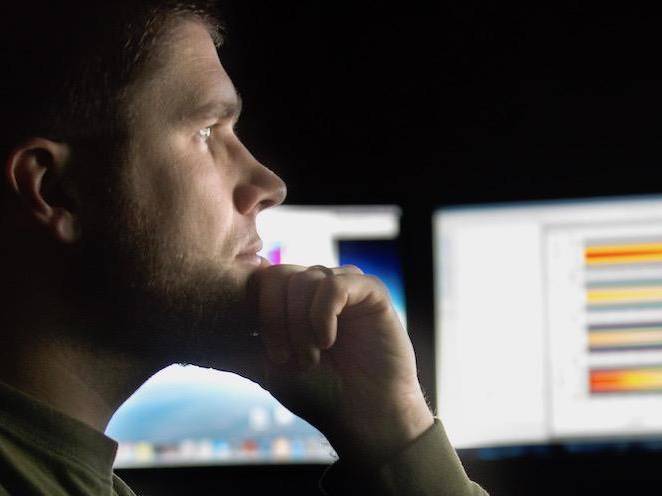 Man looking at computer monitors of colorful graphs