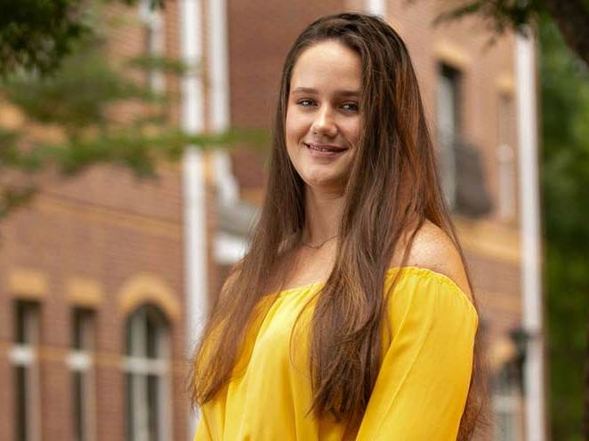 Woman standing infront of a building smiling for a picture