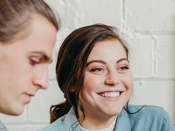 Man is focusing and the woman is seated beside him smiling for picture