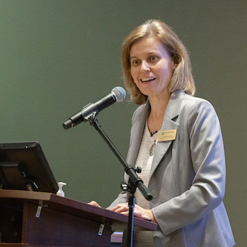 Woman with tablet infront of her speaking through a microphone