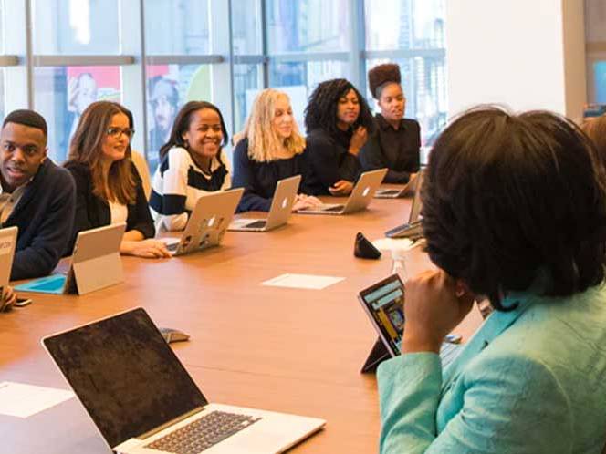 Large group of men and women sitting at a table communicating with eachother