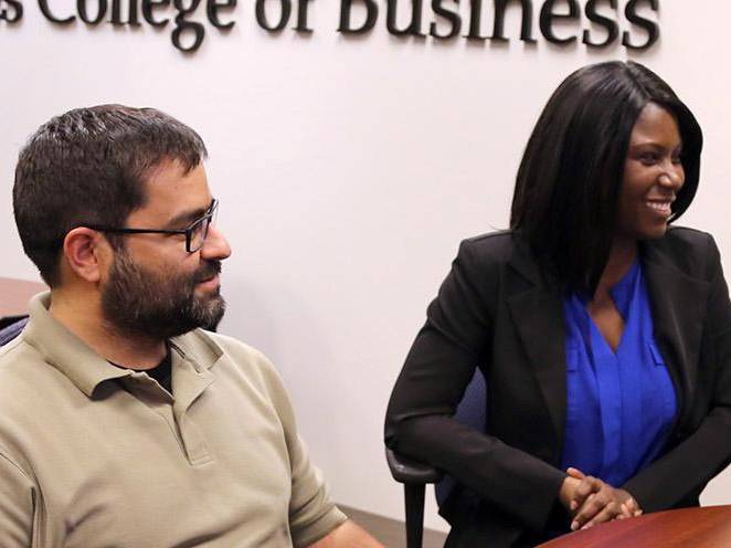 Man and woman sitting in the College of Business room communicating