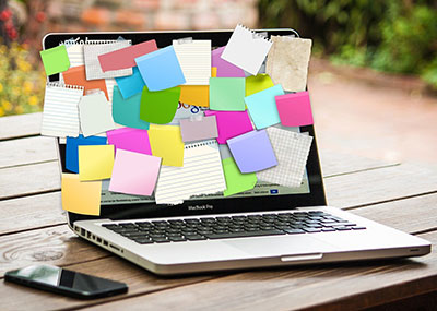 A laptop fully covered in colorful sticky notes