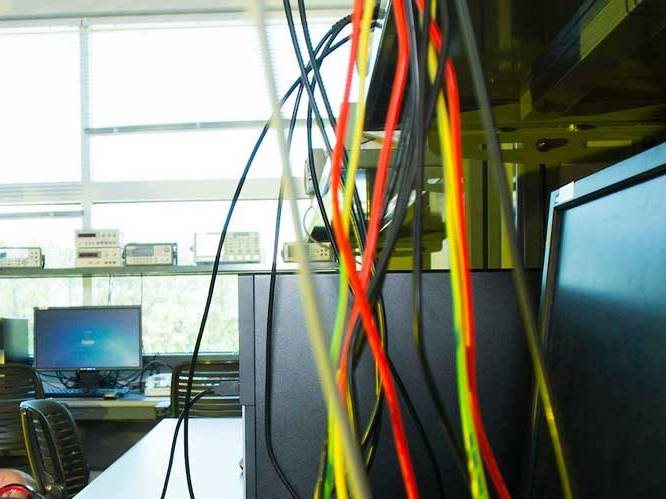 A computer monitor with different color wires hanging down infront of it