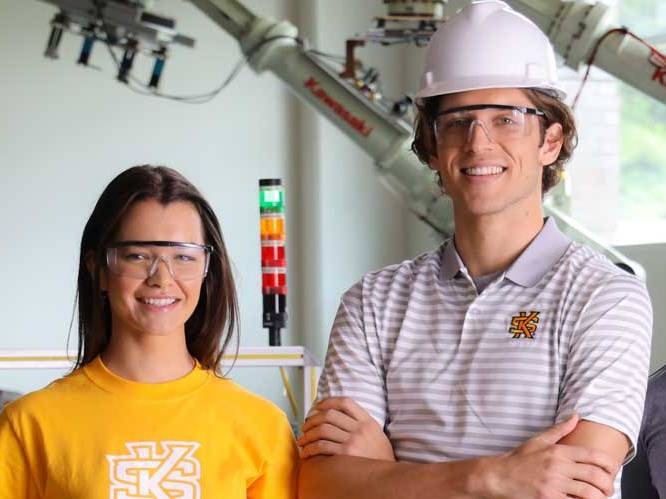 Man and woman with safety glasses and a construction hat smiling for a picture