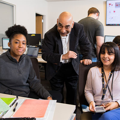 Software Engineering BS / Information Technology MS Students at desk with teacher assisting them