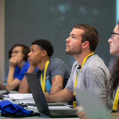 Students at desk looking up focusing