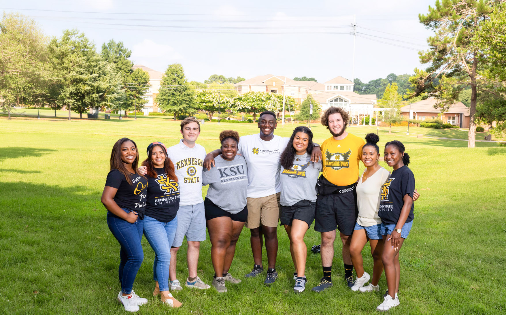 ksu students smiling outside holding eachother by the shoulders