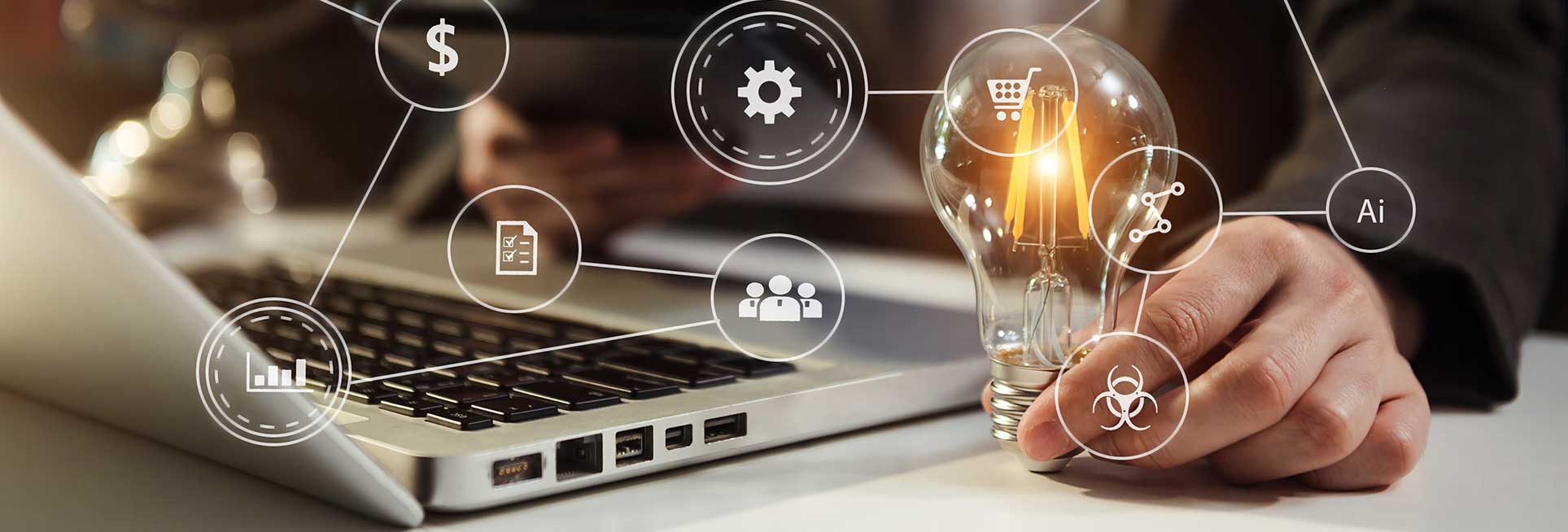 entrepreneur at laptop with lit lightbulb in hand with entrepreneurial icons