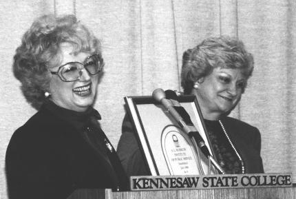 two ksu burruss institute staff ladies laughing at podium