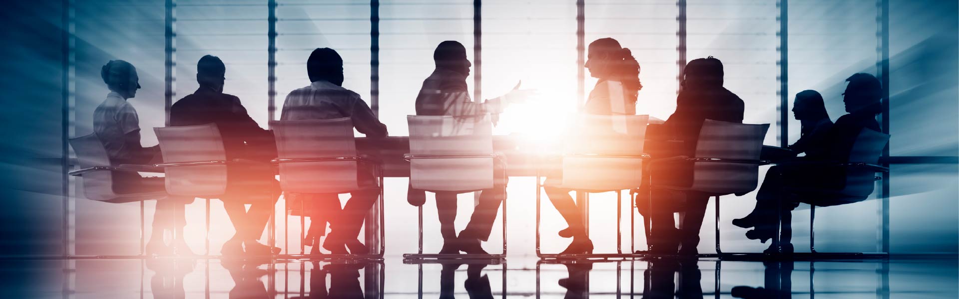 Business people sitting at a table in front of a window with the sun shining through