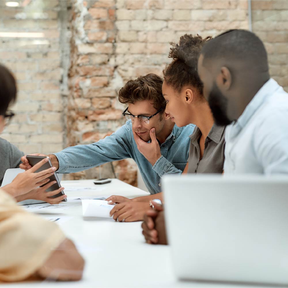 group of people at a table looking at papers and tablets 