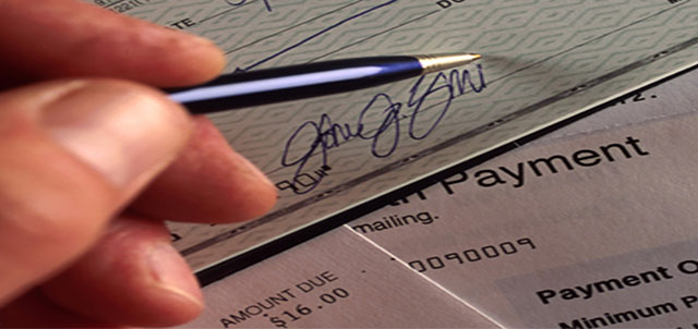 A hand signing a check