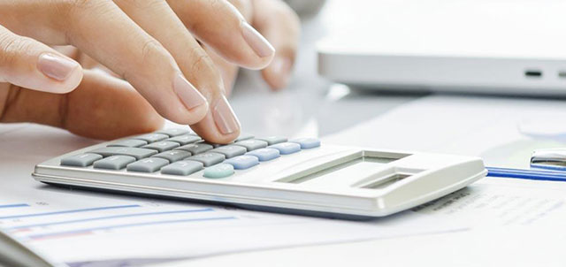 A hand typing on a calculator