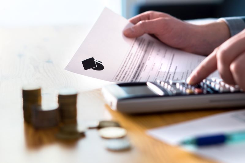 Man using calculator and holding a tuition document