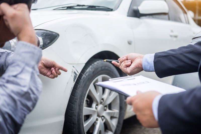 Two people looking at damage done to a white car