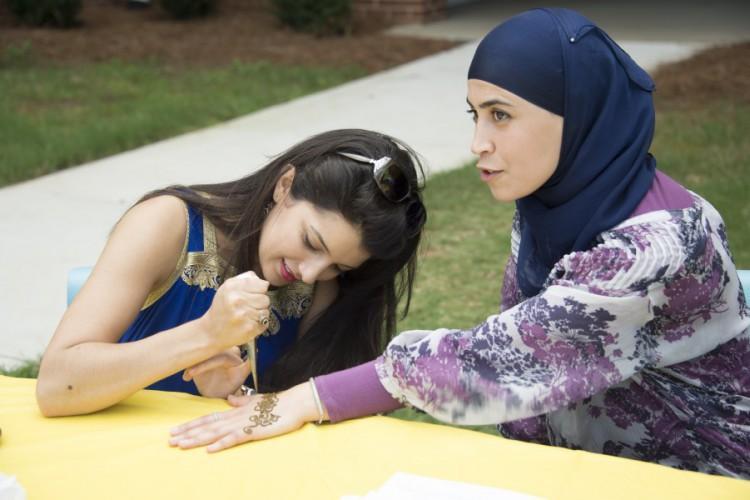  / Saloua Lahlou, henna hand painting artist from Alif Institute, paints the hand of Ilham Ramram, a Kennesaw State alum from Morocco.