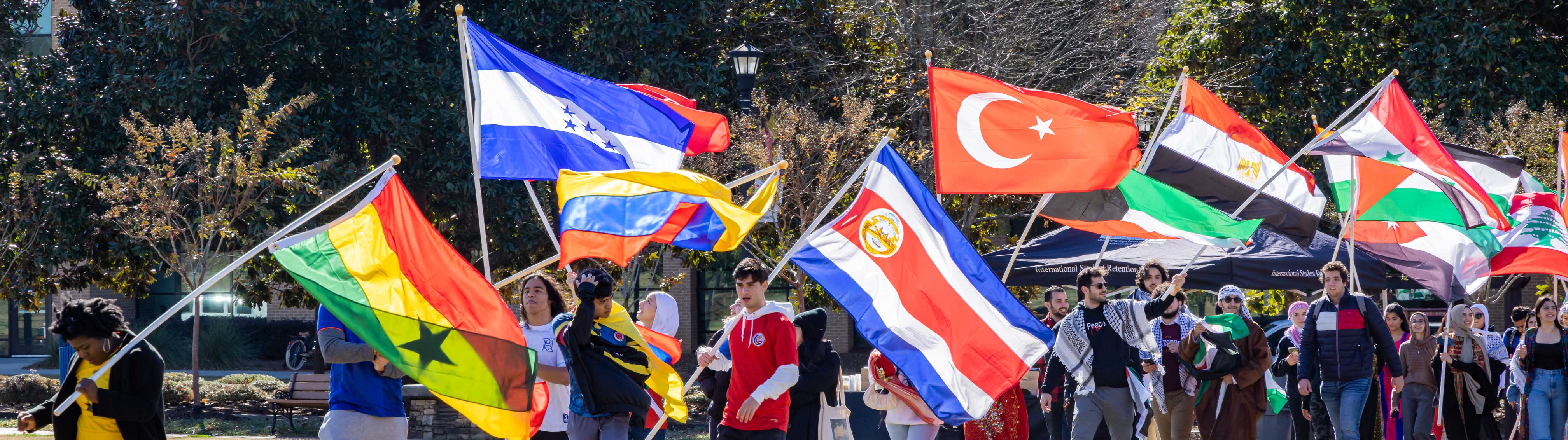 international student carrying various country's flags across ksu green
