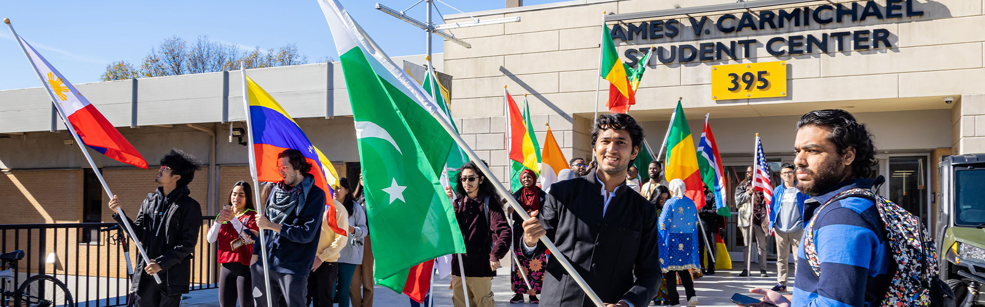 A group of international students outside the Kennesaw Student Center waving international flags