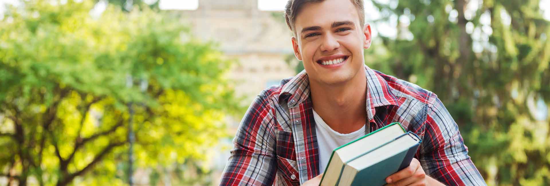 young man smiling  holding books