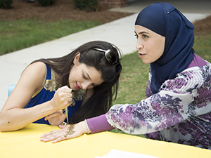 KSU female student giving another student a henna tattoo