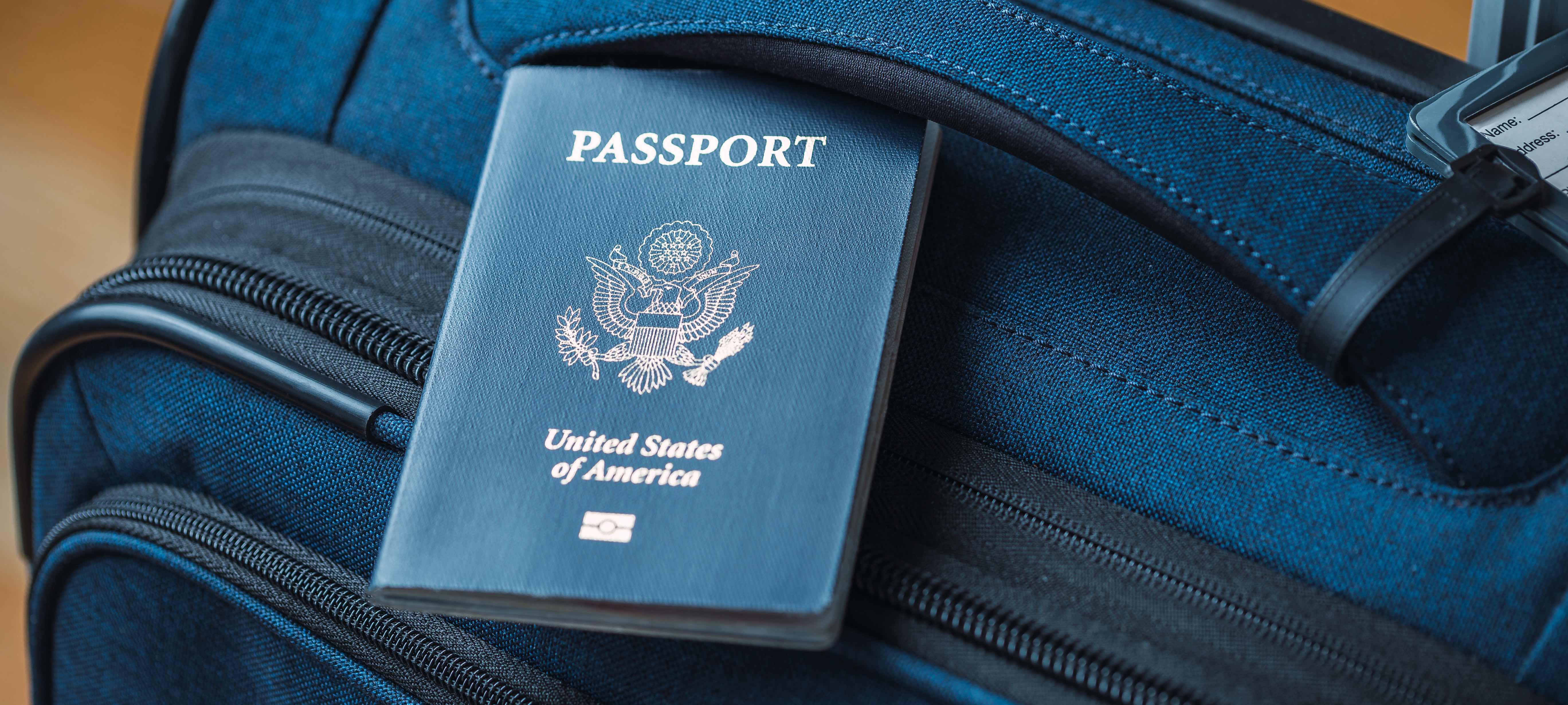 A blue American passport sitting on top of a blue suitcase