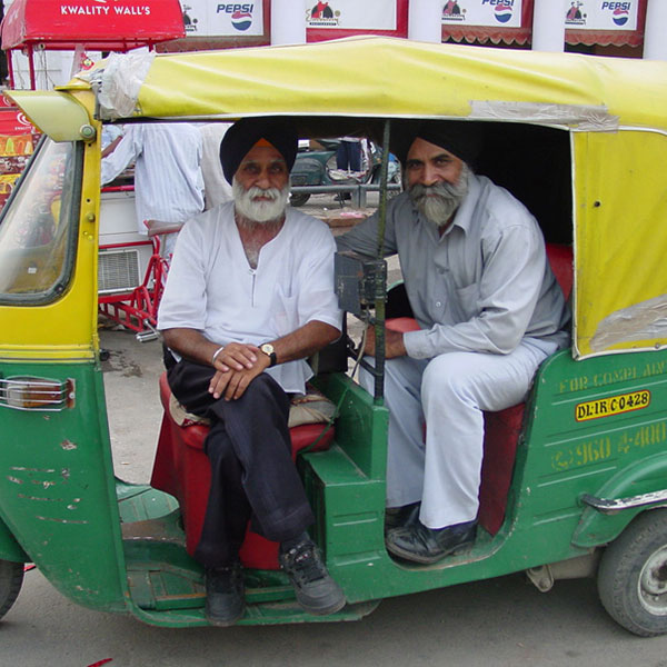 Two men in India in a small green car.