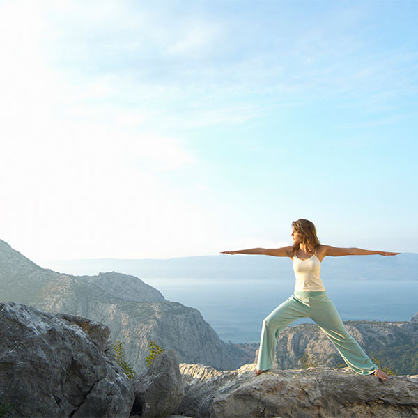 Woman doing yoga on the mountain.