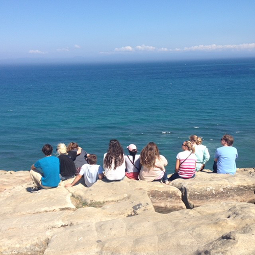 group of group of KSU student siting on cliff overseeing ocean