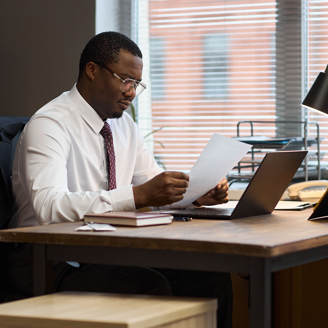 An education professional reviews documents at a desk in an office environment.