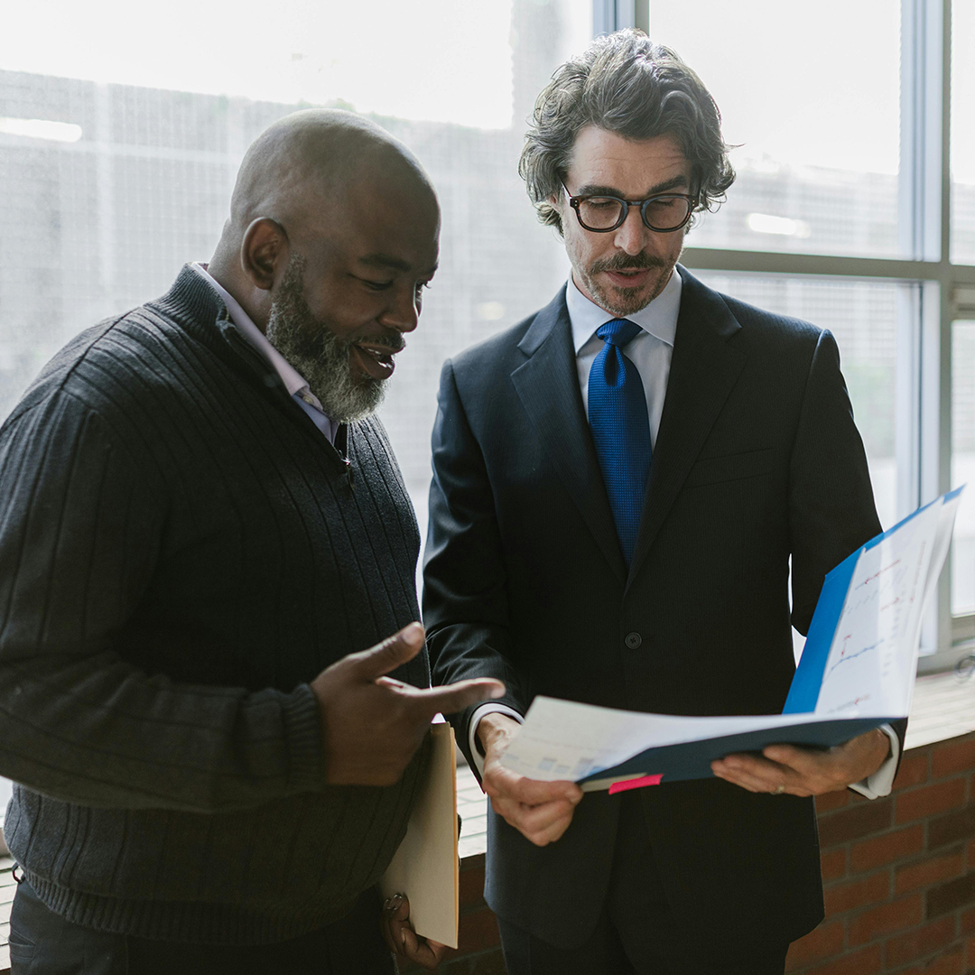 Two men in office looking at documents in their hand