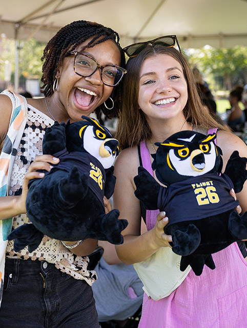 Two females, each with their Flight 26 owl, enjoy a special KSU tradition of stuffing an owl during Welcome Week activites.